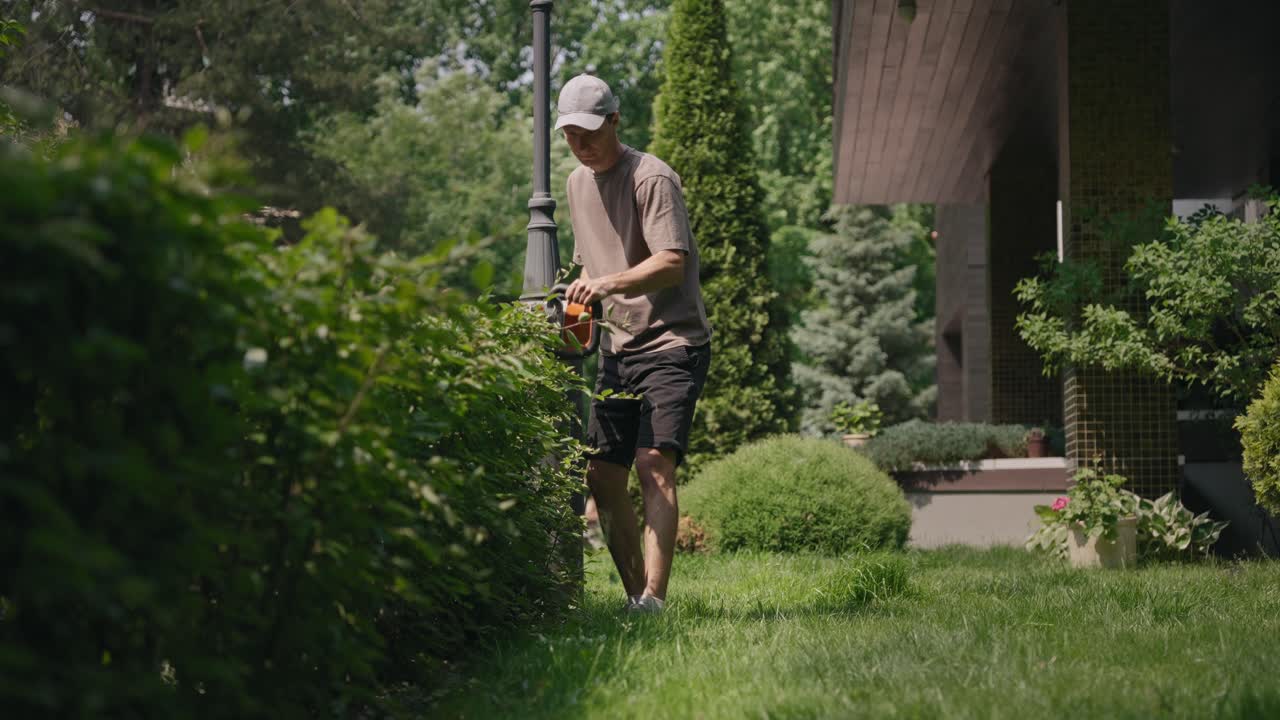 Man Trimming Green Hedge in a Residential Garden