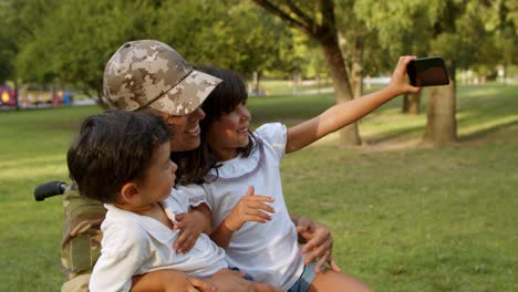 happy disabled military dad in wheelchair and two kids talking selfie