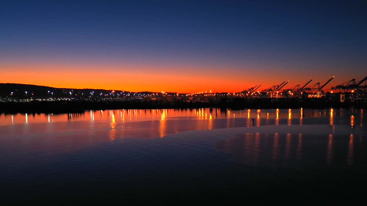High definition hyper-lapse time compression long speed film of a beautiful sunrise over a large industrial shipping port.