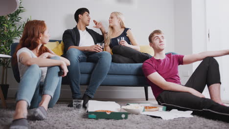 grupo de estudiantes universitarios en una casa compartida viendo televisión y comiendo pizza