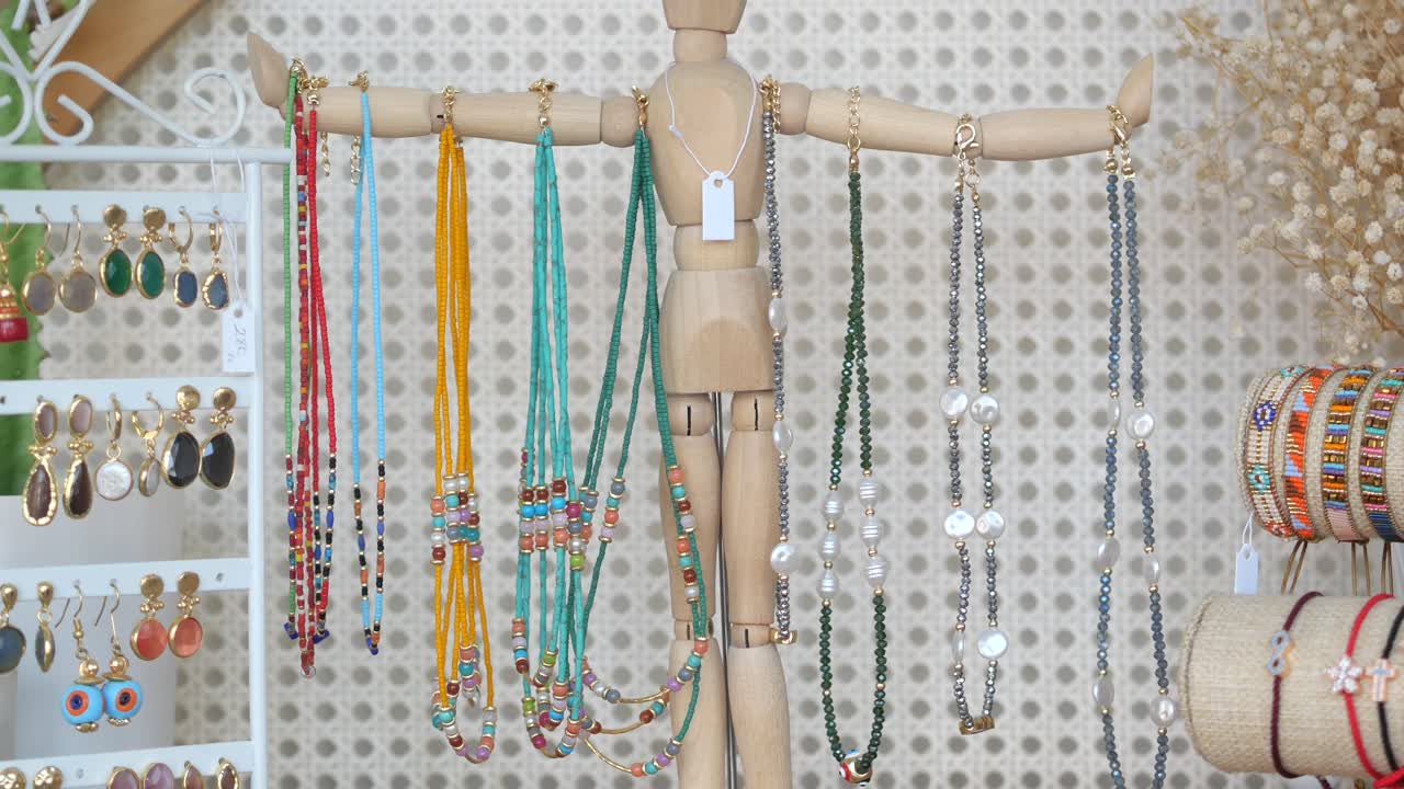 coloridos collares, pulseras y pendientes hechos a mano exhibidos en maniquíes de madera