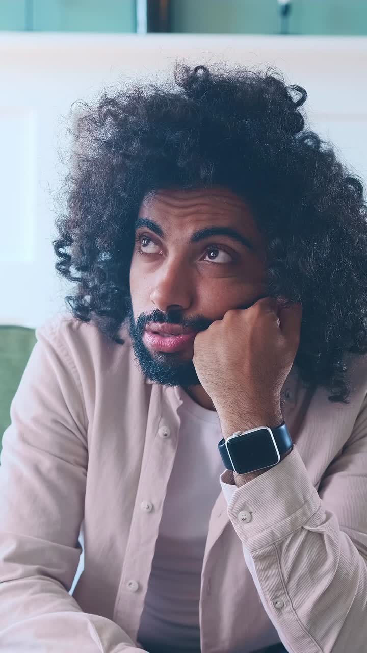 Pensive man contemplating deeply while resting his chin on his hand indoors