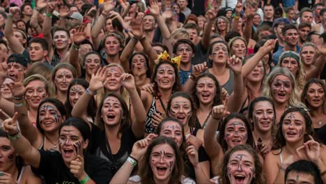 excited crowd of festival-goers celebrating together with painted faces and cheerful expressions, capturing the joy and energy of a live music experience
