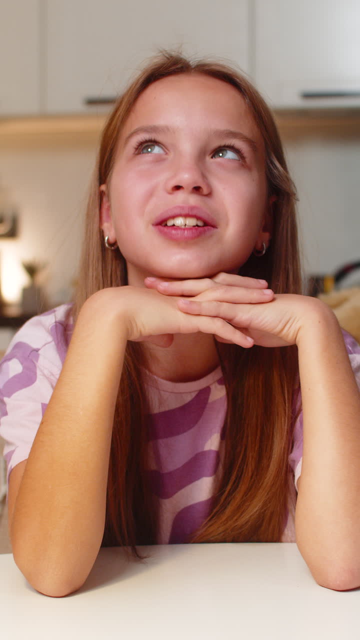 Ragazza adolescente con il mento appoggiato sulle mani che guarda in su, pensando al futuro, con un sorriso dolce e un'espressione sognante e calma
