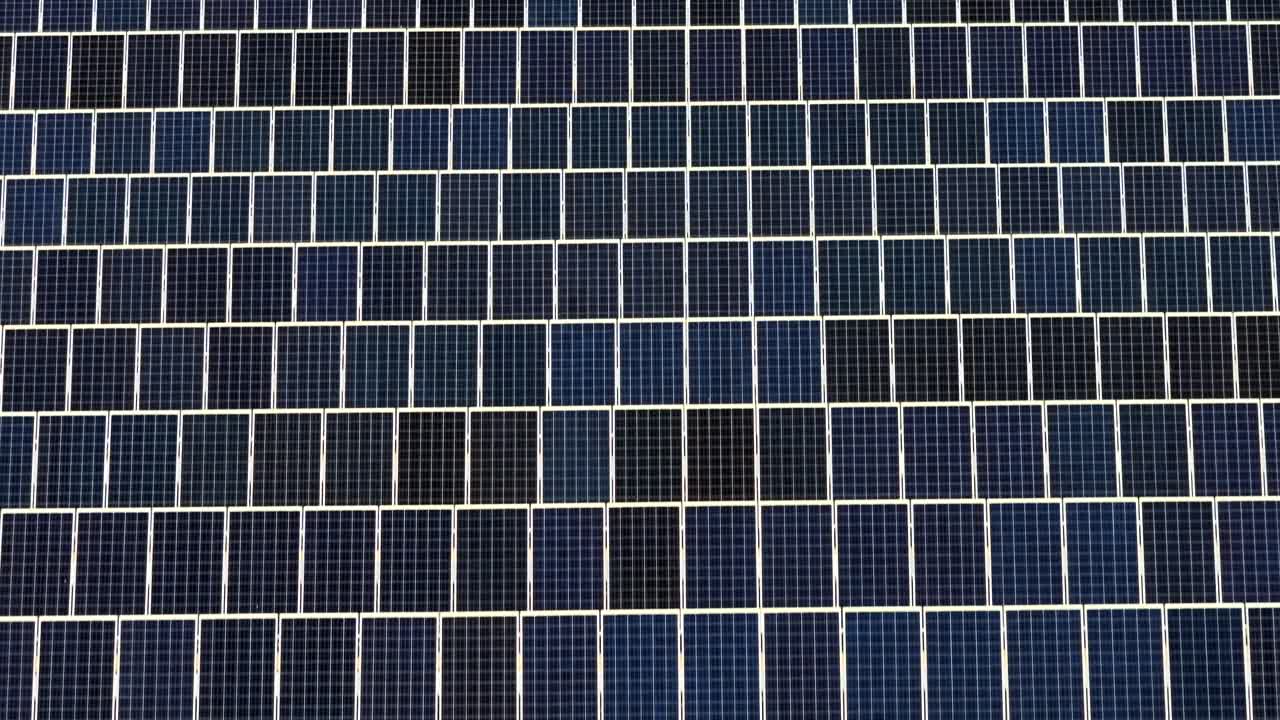 Un campo infinito di pannelli solari che convertono la luce solare in energia rinnovabile - sorvolo aereo