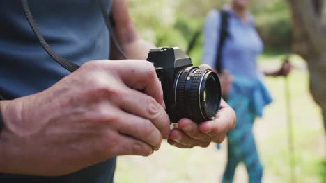 mid section of senior man using digital camera to take pictures in the woods while hiking