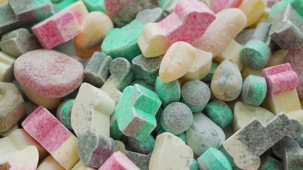 한 남자가 큰 사탕  ⁇ 어리에서 두 개의 사탕을 집어 들고 있다.