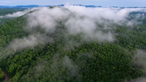 Volando-A-Través-De-Nubes-Blancas-Bajas-Sobre-El-Bosque-Verde-De-Las-Grandes-Montañas-Humeantes