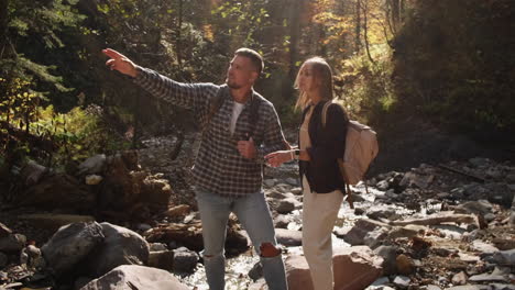 couple hiking through a mountain stream in autumn