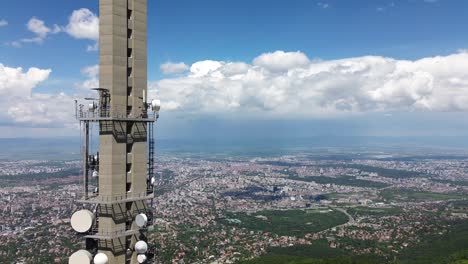 Toma-De-Ascensor-Con-Vistas-A-Una-Gran-Ciudad,-Con-Una-Torre-De-Televisión-En-Primer-Plano-Una-Torre-De-Televisión