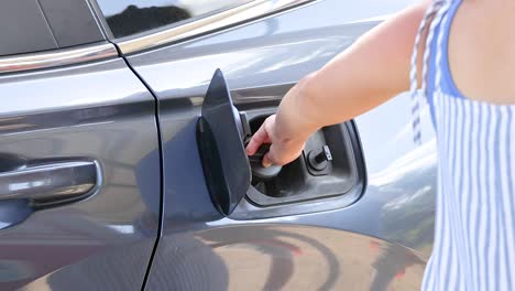 a person opens a car's fuel tank cap under bright daylight in phuket, thailand