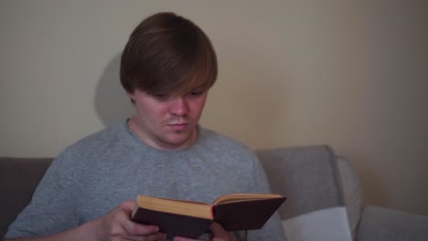 young man reading a book on a sofa