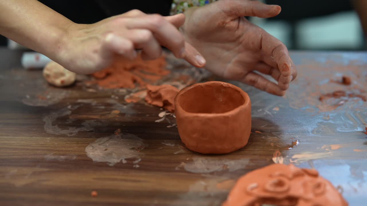manos que dan forma a las ollas de arcilla
