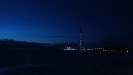 night view of a skyscraper over a frozen river