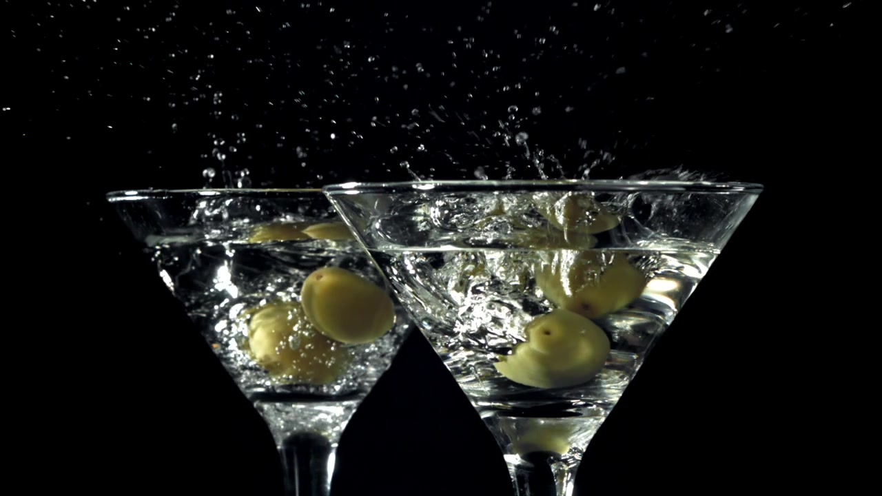 Olive verdi che cadono in cocktail Martini al rallentatore