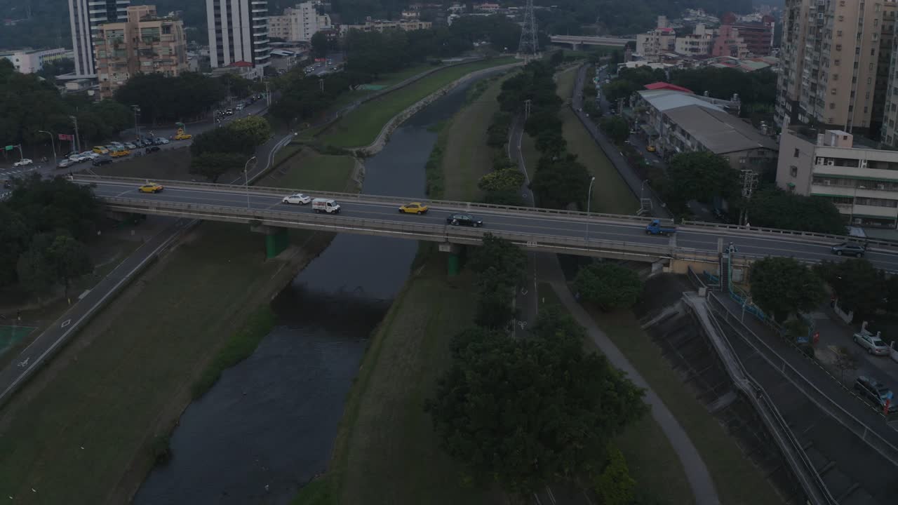 un dron se centró en un motociclista que cruzaba un puente en taipei al atardecer