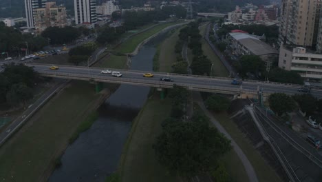 A-drone-shot-focused-on-a-biker-riding-through-a-bridge-in-Taipei-at-dusk