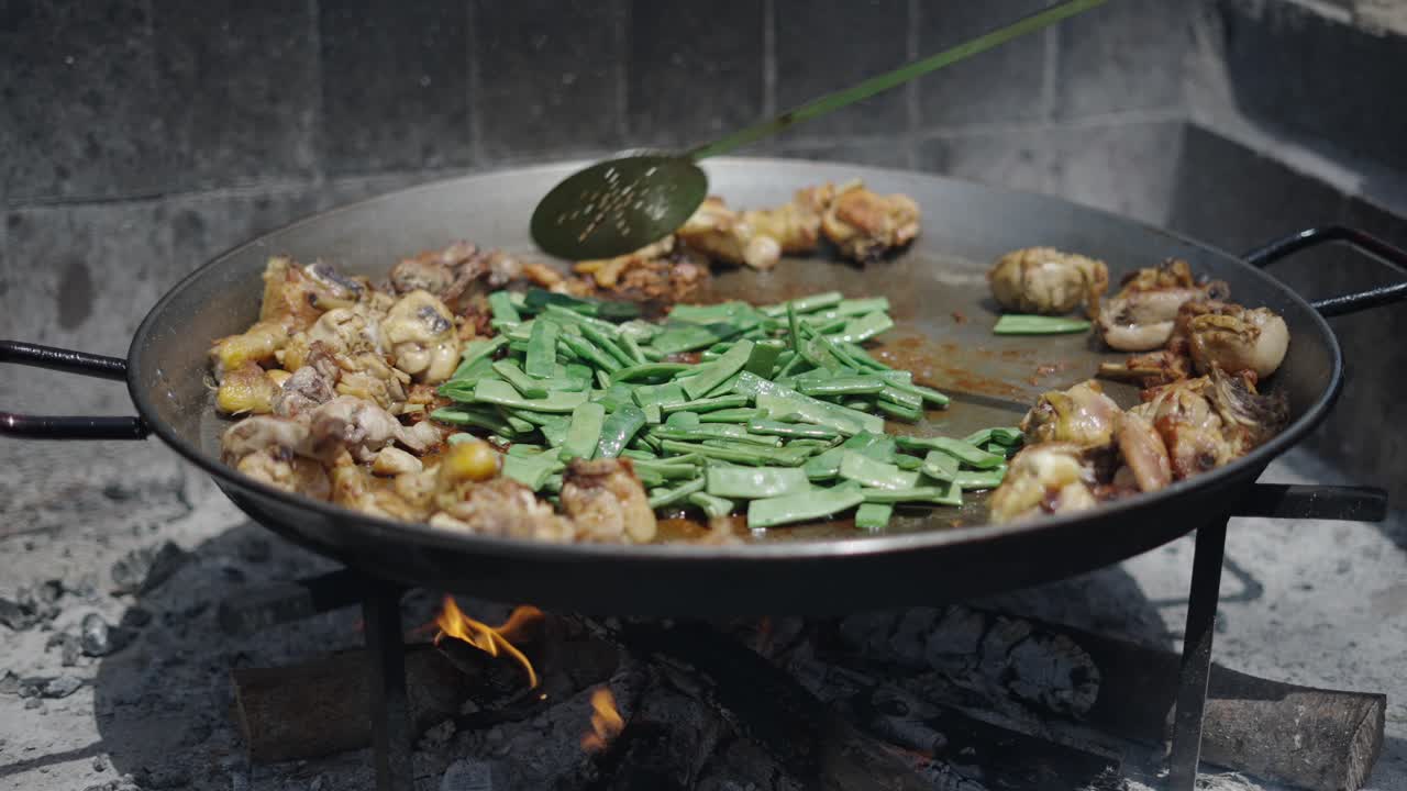Cooking Chicken and Green Beans in a Large Pan Over an Open Fire