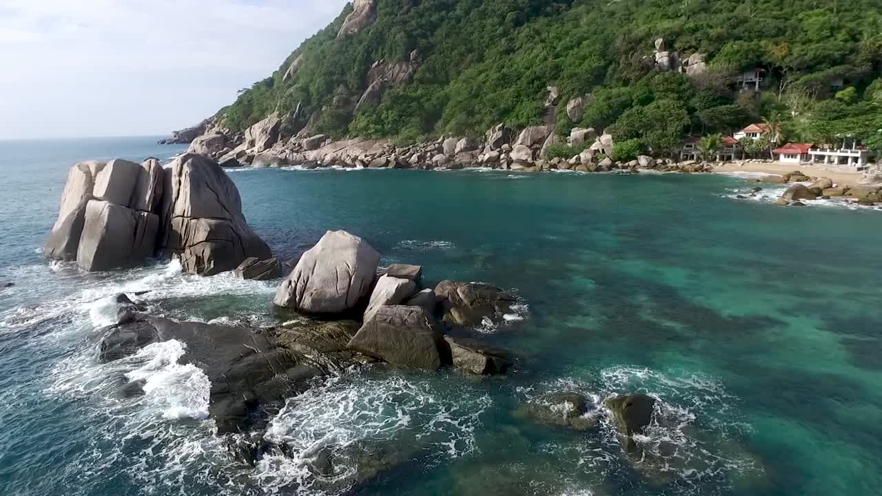 olas golpeando rocas volando alrededor del fondo de la palmera cerca de la isla