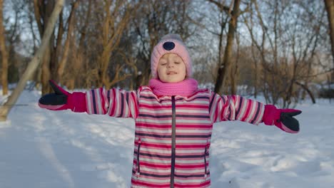 a young girl plays in the snow during winter