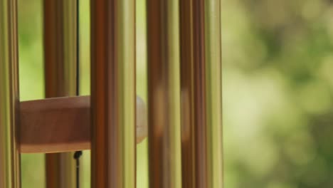 metal wind chime closeup natural green background slow motion 120p