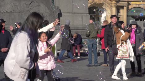 crowd of people and children playing with soap bubbles in prague main square