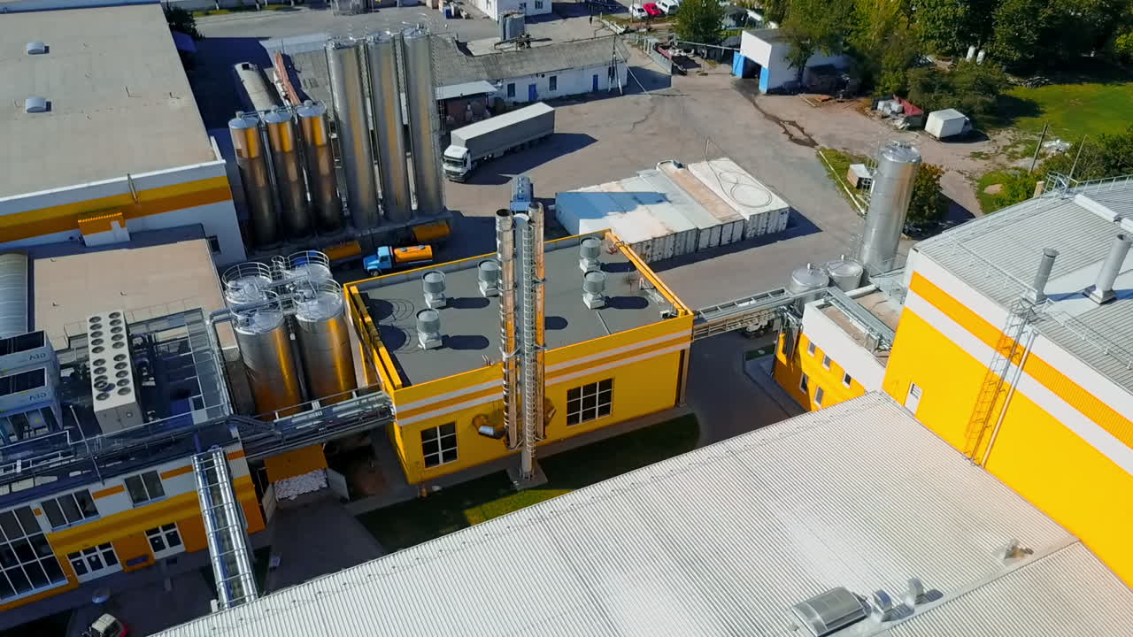 Grey lorry moving by the territory of the modern industrial plant. Premises of the factory on sunny day from aerial view.