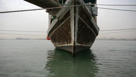 old wooden dhow boat is slowly rocking in harbor of doha