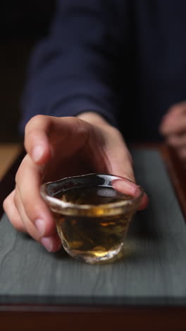 person holding a small glass cup of tea