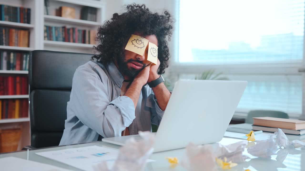 Young african american man freelancer sits and sleeping with stickers closed