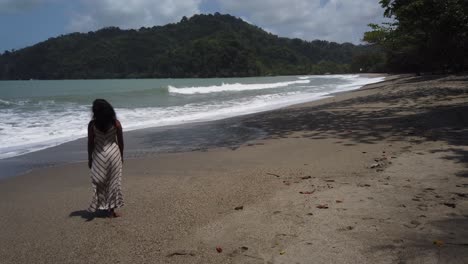 A-model-walking-in-to-the-ocean-while-the-waves-break-at-shoreline