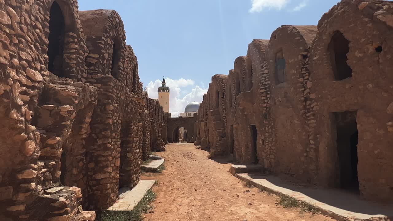 caminando por las ruinas de la aldea de ksar hadada en túnez con una mezquita en el fondo