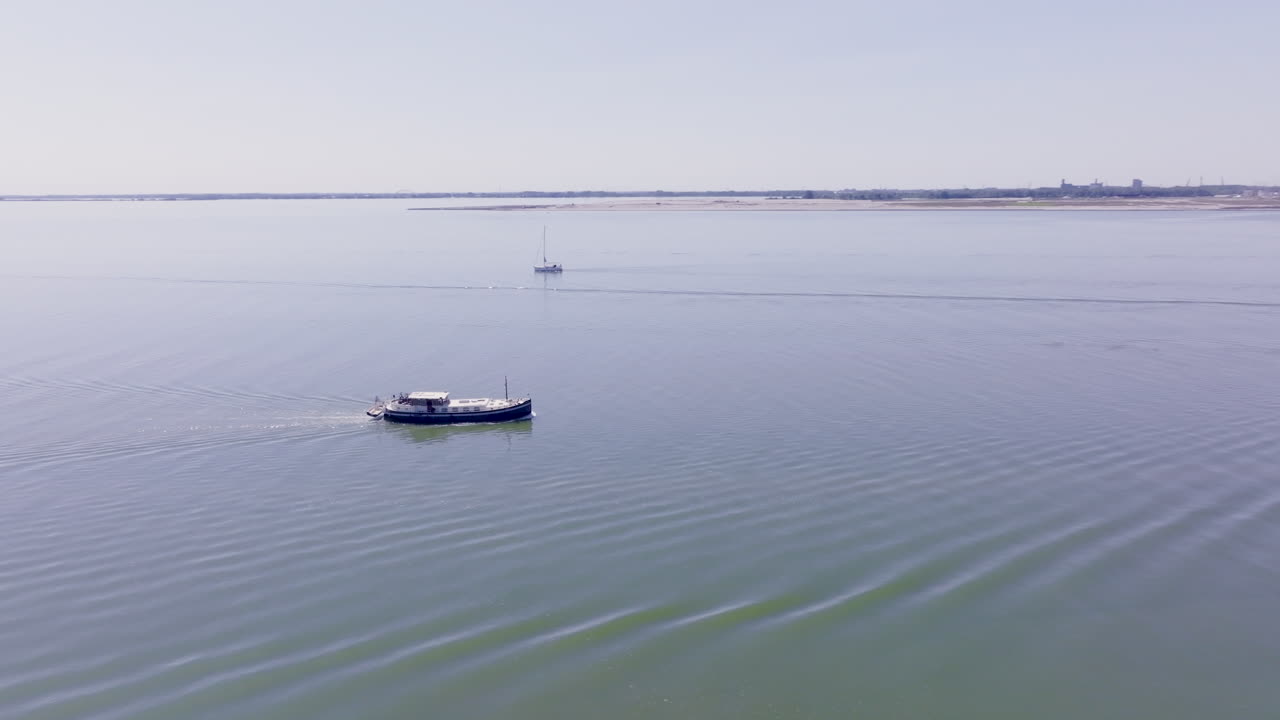 A Luxemotor boat cutting through calm, reflective waters in the Dutch province of Flevoland