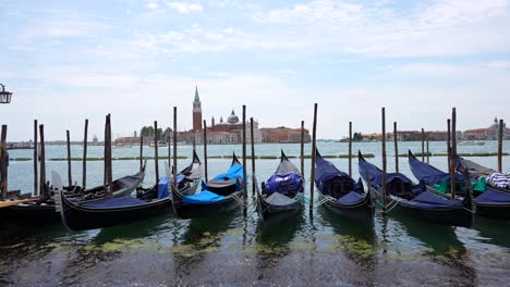 Mujer-Caminando-En-Góndolas-Con-La-Basílica-De-San-Giorgio-Maggiore-Al-Fondo,-Venecia