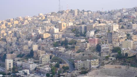 pan lento de la ciudad capital, amman, en jordania, con un gran número de casas, edificios, calles y tráfico.