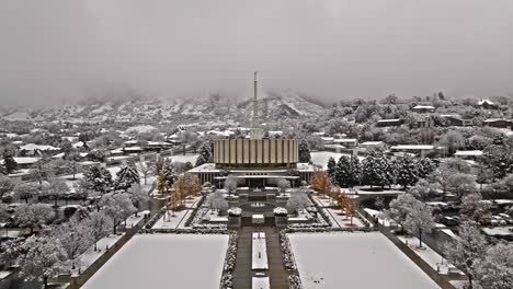 Symmetrischer-Dolly-Aus-Der-Luft-Schiebt-Sich-Hinein,-Um-Den-Mormonentempel-Im-Schnee-Zu-Provozieren,-Dahinter-Die-Wasatch-Bergkette