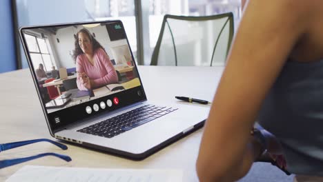 Mujer-Afroamericana-Usando-Una-Computadora-Portátil-Para-Videollamadas,-Con-Un-Colega-De-Negocios-En-La-Pantalla