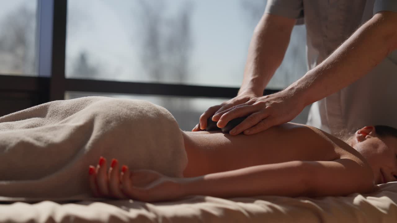 Kvinde modtager hot stone rygmassage i et spa