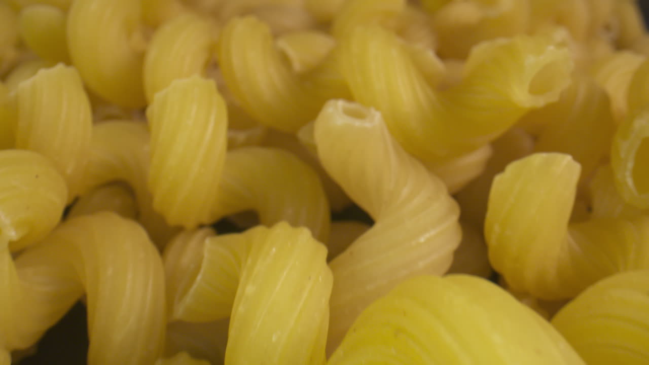 diapositiva macro a través de un montón de pasta tortiglioni seca