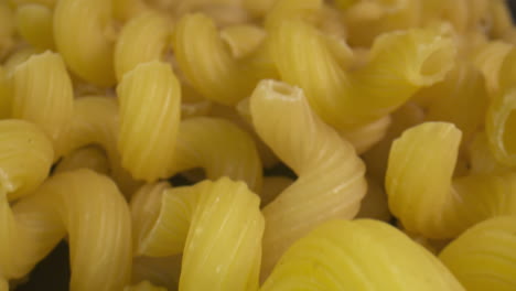 macro slide across a pile of dry tortiglioni pasta