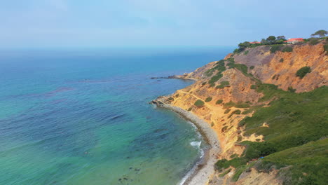 picturesque view of a beach with turquoise ocean waves gently breaking on the sandy beach at palos verdes, california pull back aerial view