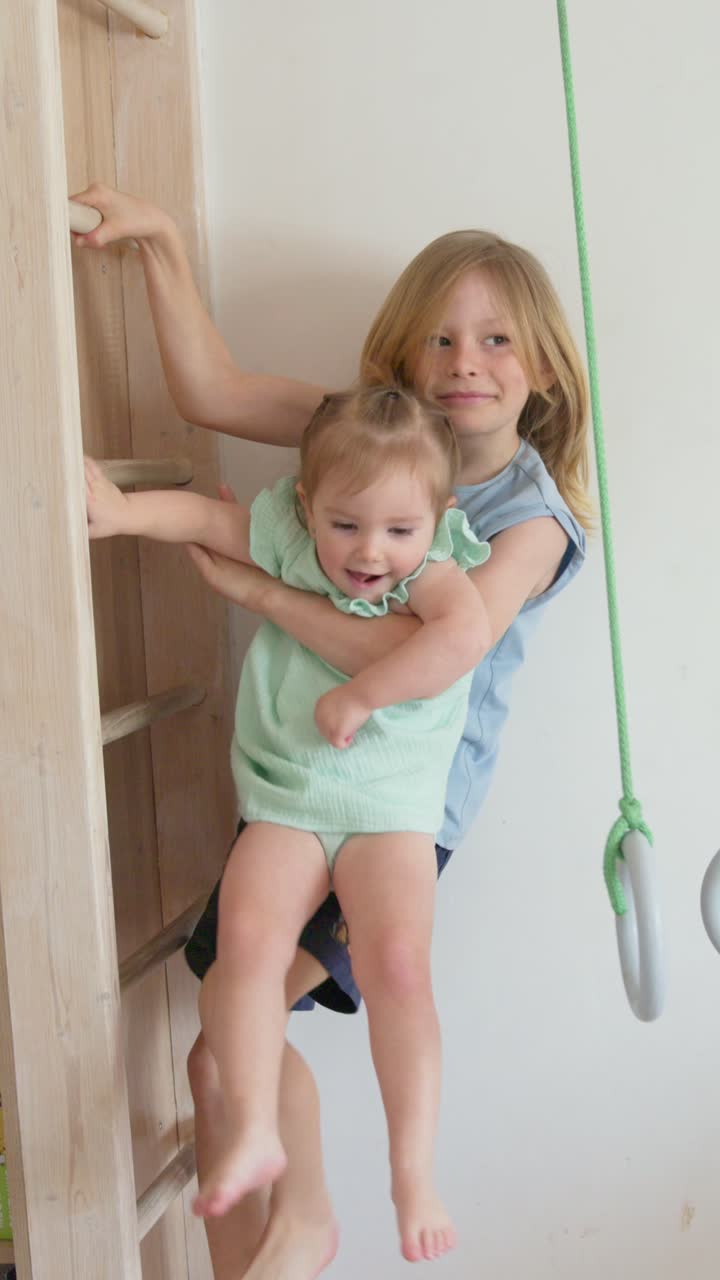 Older Sister Helps Younger Sister Play on Wall Bars