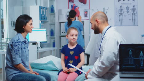 Doctor-talking-with-little-girl-sitting-on-bed