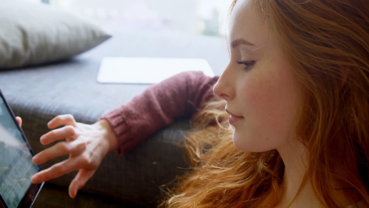 Woman using digital tablet in living room 4k