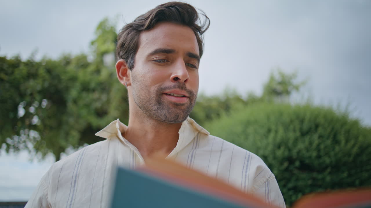 소설을 큰 소리로 읽는 멋진 남자 여름 공원 클로즈업 혼자 책을 즐기는 마초