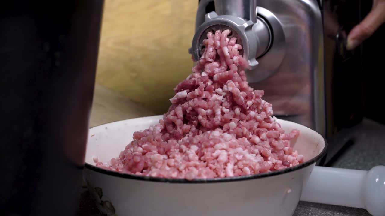 Pilha de carne de porco moída com máquina elétrica em mesa doméstica.