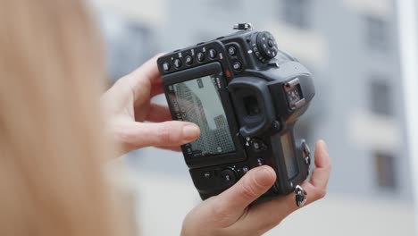 woman holding a dslr camera, viewing the image on the lcd screen