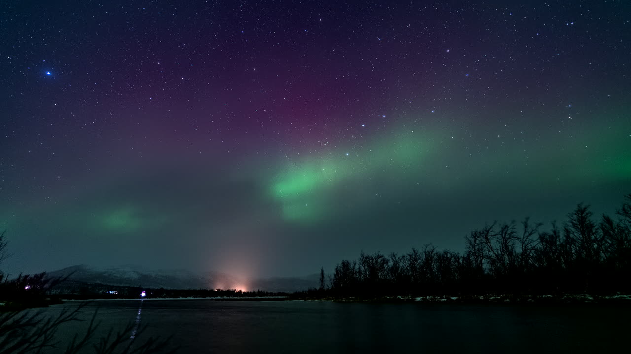 las vibrantes luces del norte bailando en el cielo estrellado de la noche, vista en lapso de tiempo sobre el río