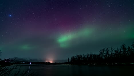 las vibrantes luces del norte bailando en el cielo estrellado de la noche, vista en lapso de tiempo sobre el río