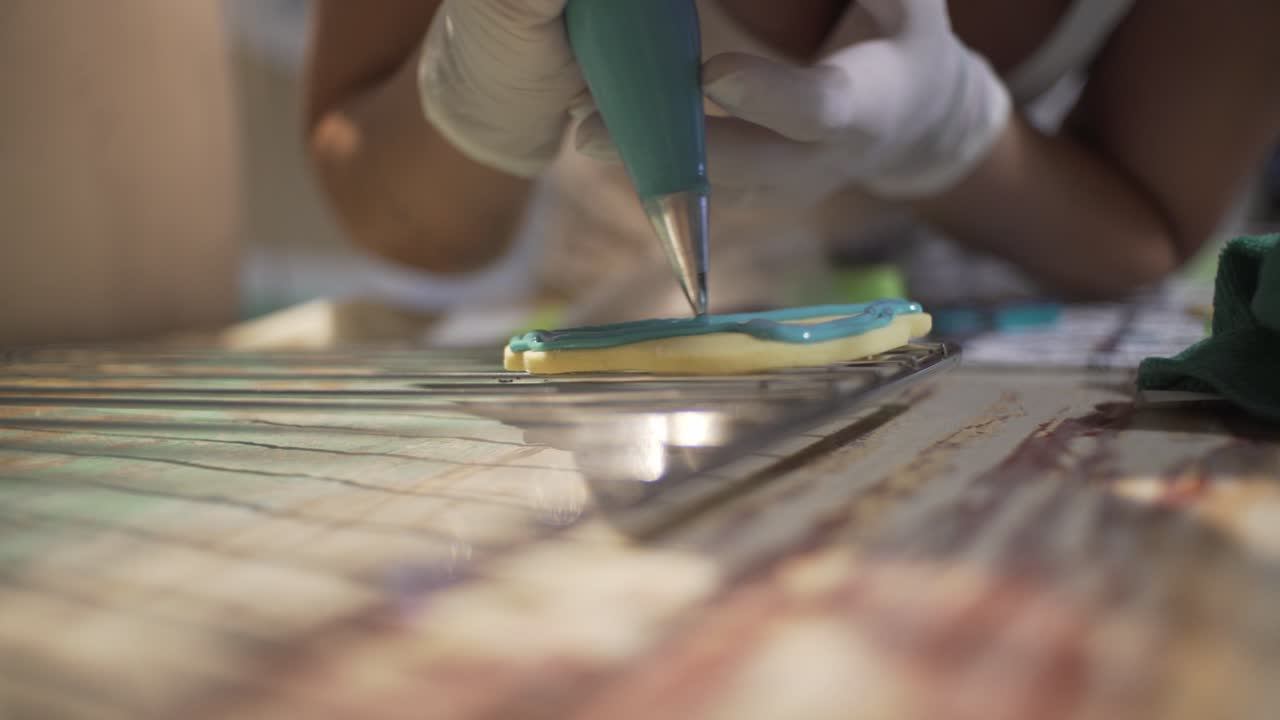mujer decora galletas caseras en forma de vehículo con azúcar glas usando una manga pastelera